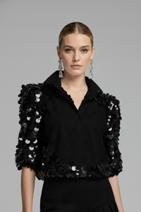 Modelo con blusa Sparkling negra con panel frontal liso y mangas de tul bordadas con lentejuelas negras que aportan brillo sofisticado | Claudia Bertolero