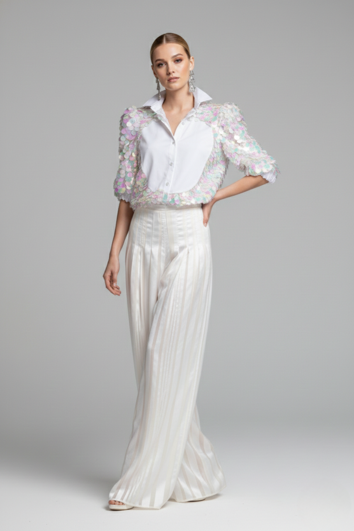 Modelo luciendo blusa Sparkling blanca con panel frontal de popelina y mangas 3/4 de tul con lentejuelas multicolor aplicadas a mano y pantalón Celestial de organza y raso | Claudia Bertolerlón