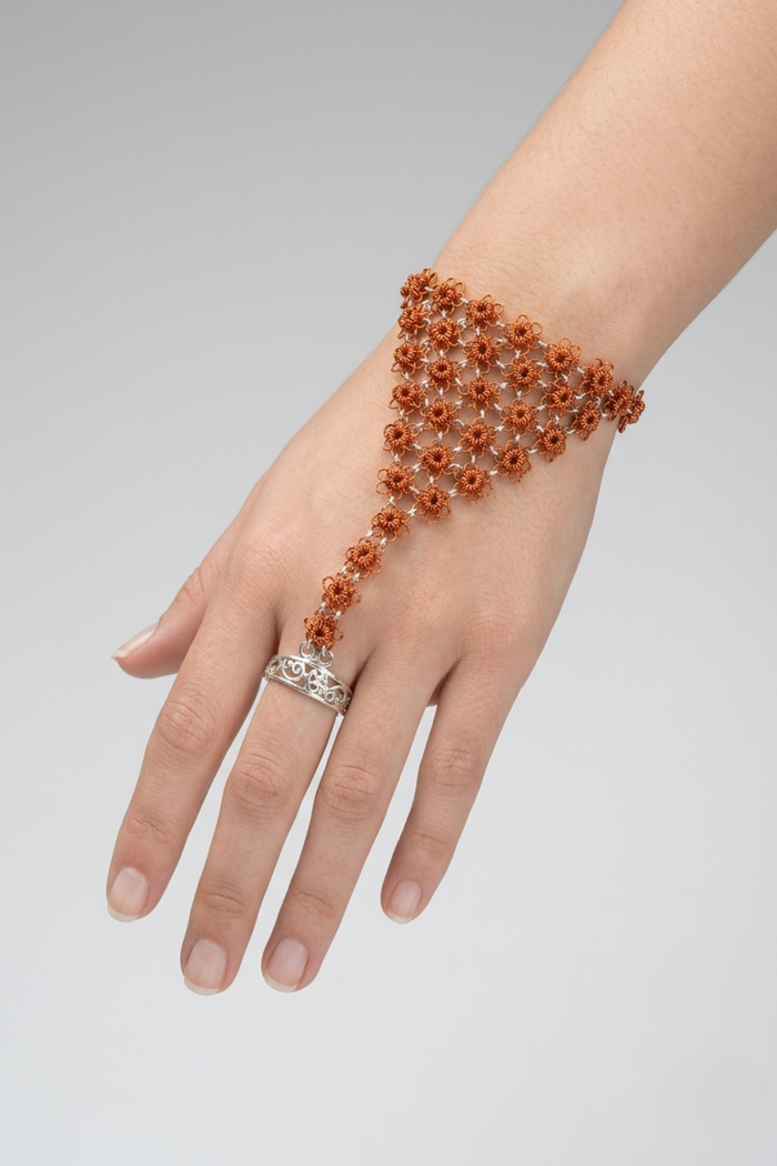 Brazalete Mi Encanto de flores tejidas en hilo de cobre con uniones en plata 950 y anillo regulable de plata, usado como accesorio de mano | Claudia Bertolero