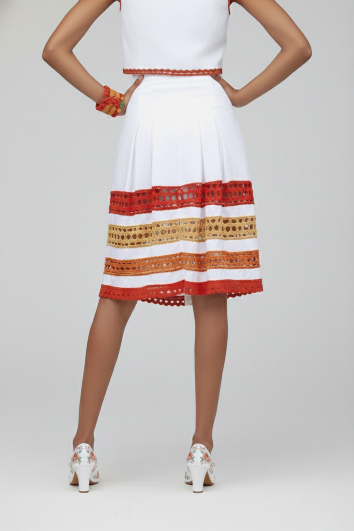Falda Short Tribal blanca con franjas horizontales de crochet rojo, naranja y beige en el ruedo, vista posterior | Claudia Bertolero