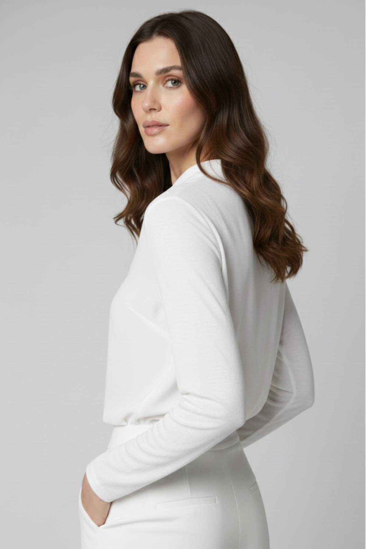 Vista lateral de la Blusa Renoir en color blanco, confeccionada en viscosa suave. La modelo gira ligeramente mostrando la caída natural de la tela y la comodidad de las mangas largas | Claudia Bertolero