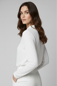 Vista lateral de la Blusa Renoir en color blanco, confeccionada en viscosa suave. La modelo gira ligeramente mostrando la caída natural de la tela y la comodidad de las mangas largas | Claudia Bertolero