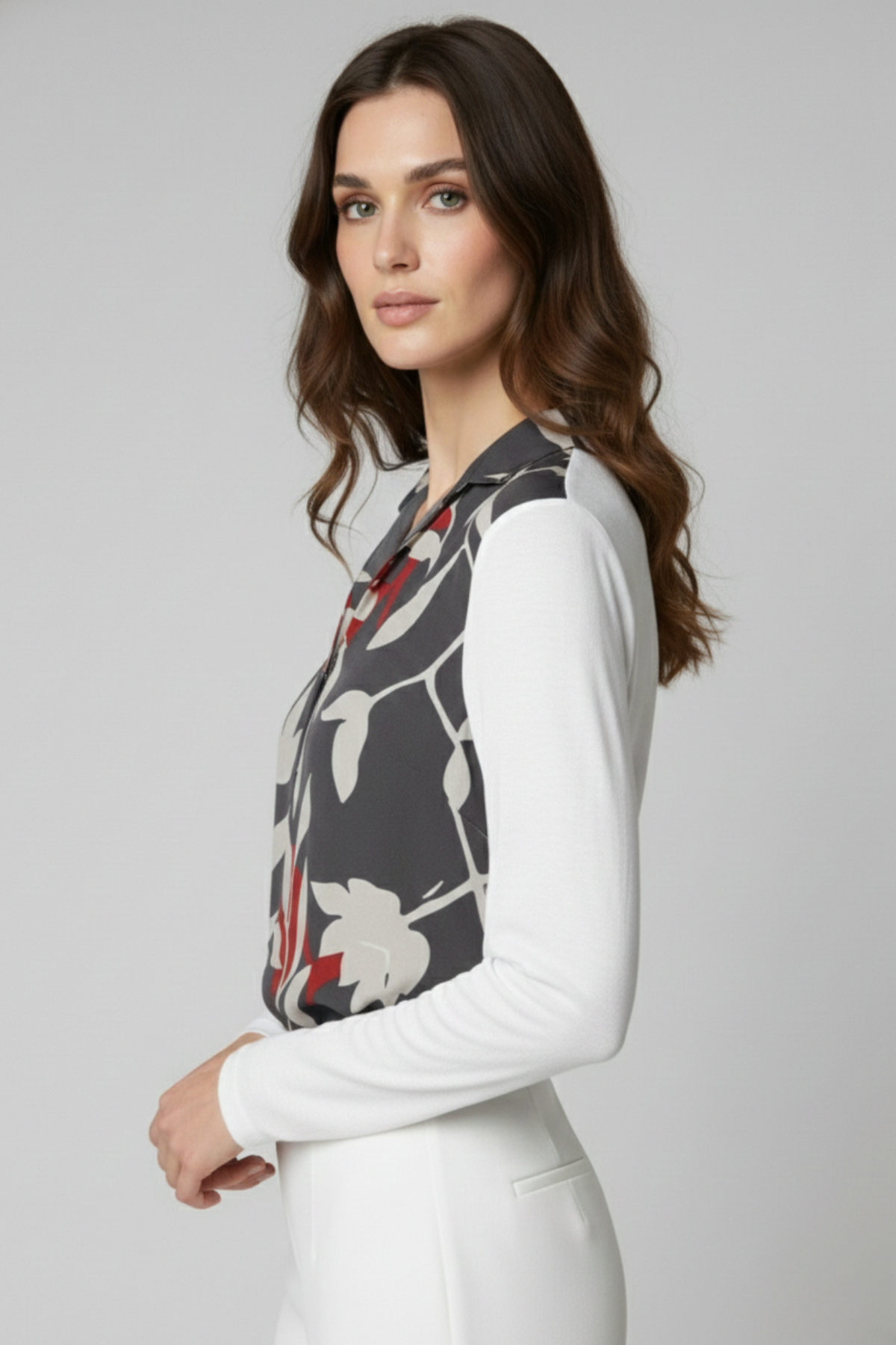 Vista lateral de la Blusa Renoir con panel frontal estampado en gris con flores blancas y rojas, y mangas blancas de viscosa. La imagen resalta el contraste de materiales y el movimiento de la tela | Claudia Bertolero