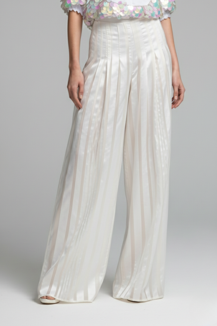 Pantalón Celestial blanco tipo palazzo con tiras de raso y organza que crean un sutil juego de transparencias, cintura alta con pliegues y caída fluida, vista frontal | Claudia Bertolero