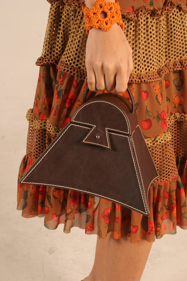 Mujer sosteniendo cartera Estribo de cuero marrón con diseño inspirado en el estribo peruano | Claudia Bertolero