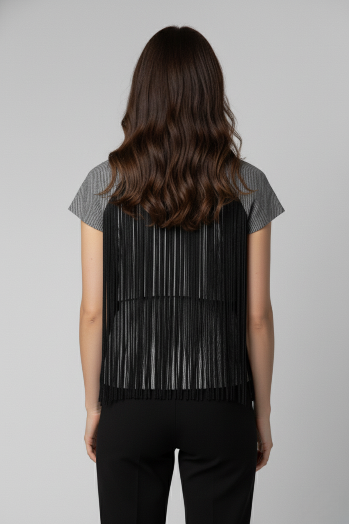 Vista posterior del bolero Batsheva gris con flecos negros largos que cubren la espalda, creando un efecto fluido y elegante | Claudia Bertolero