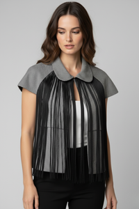 Modelo con bolero Batsheva gris de manga corta y cuello redondeado, con flecos largos negros que caen desde el frente sobre un top blanco y pantalón negro | Claudia Bertolero