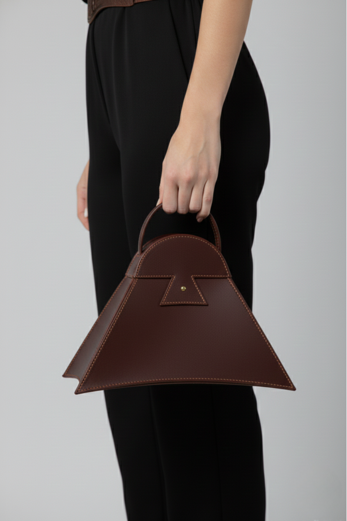 Mujer sosteniendo cartera Estribo de cuero marrón con diseño inspirado en el estribo peruano | Claudia Bertolero