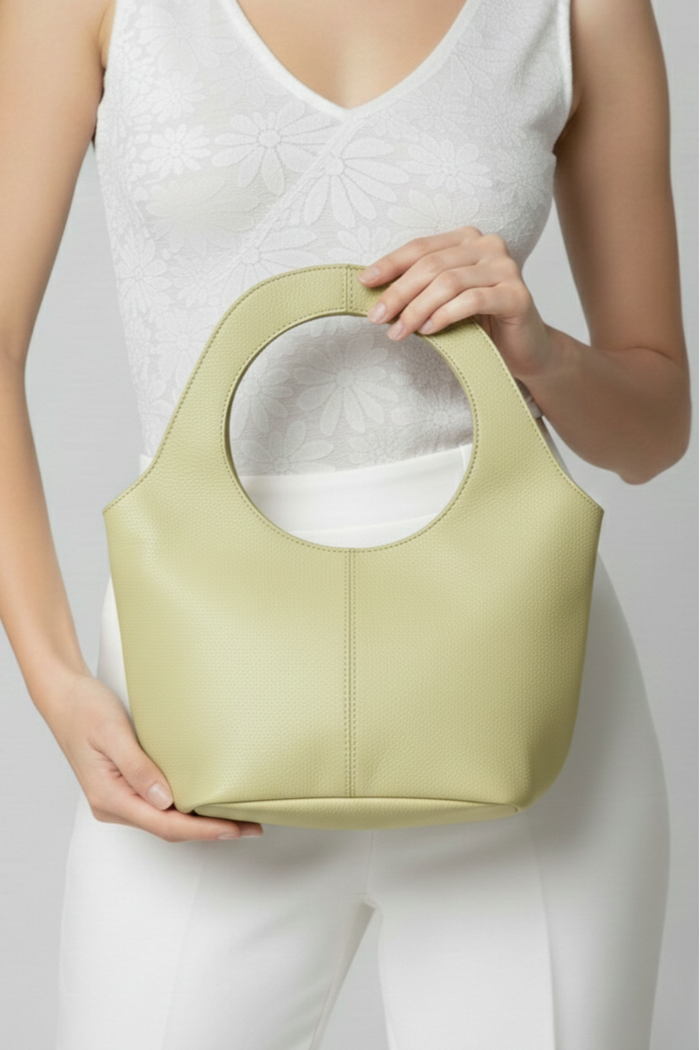 Mujer sosteniendo cartera Milan chica de cuero verde claro con asa circular | Claudia Bertolero