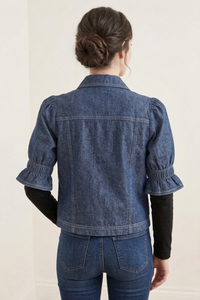 Vista posterior de la Casaca Campo en denim azul con mangas cortas estilo balloon y diseño limpio sin bolsillos, combinada con pantalón de jean | Claudia Bertolero