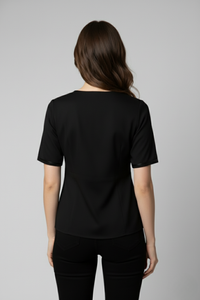 Vista posterior de la Blusa Caballero en popelina de algodón negra con mangas cortas y corte limpio en la espalda, que mantiene una silueta elegante y minimalista | Claudia Bertolero