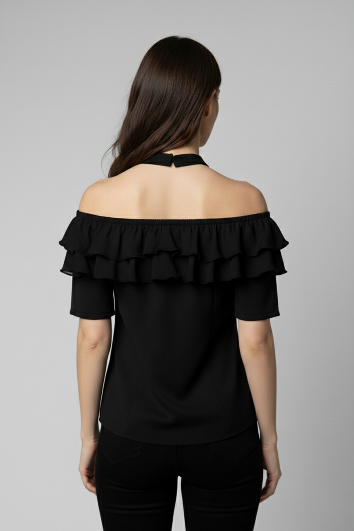 Vista posterior de la Blusa Catalina en seda negra con hombros descubiertos y cuello halter. El diseño resalta la espalda y las capas de bobos que rodean el escote con elegancia | Claudia Bertolero