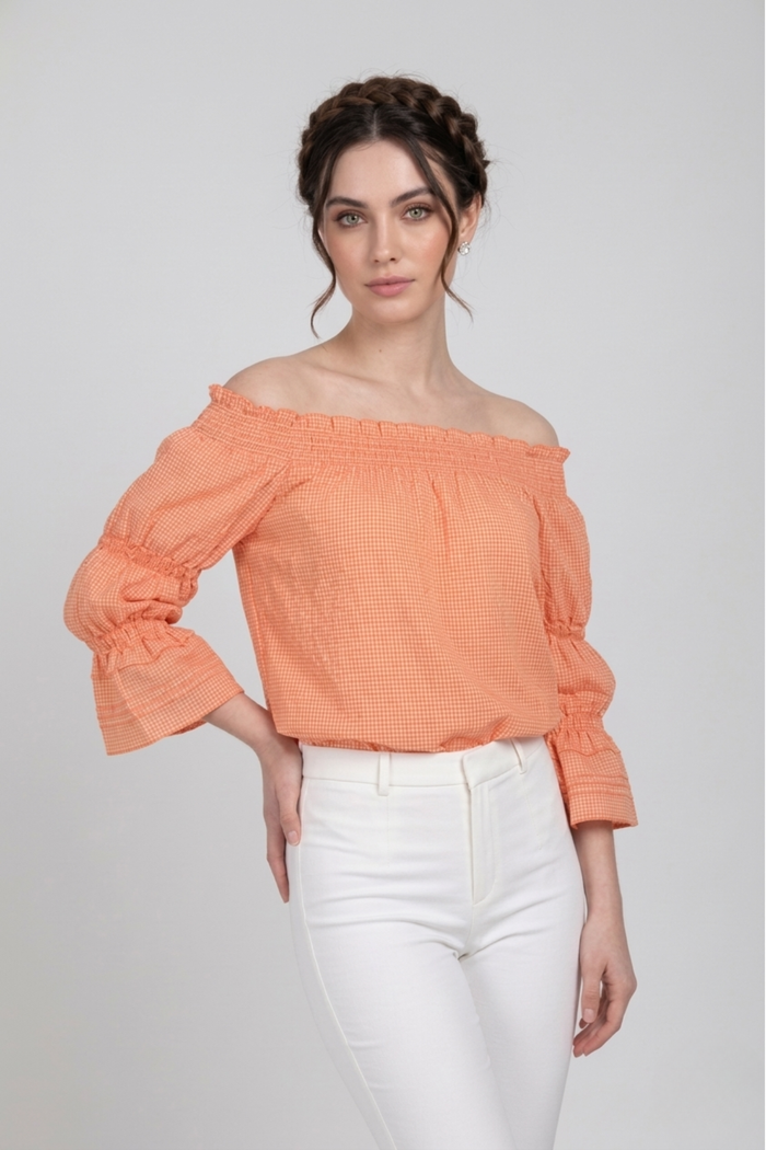 Blusa Penélope off shoulder en tela vichy de algodón color durazno con mangas largas y puños fruncidos. La silueta relajada aporta comodidad y un estilo elegante para el día | Claudia Bertolero