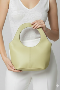 Mujer sosteniendo cartera Milan chica de cuero verde claro con asa circular | Claudia Bertolero